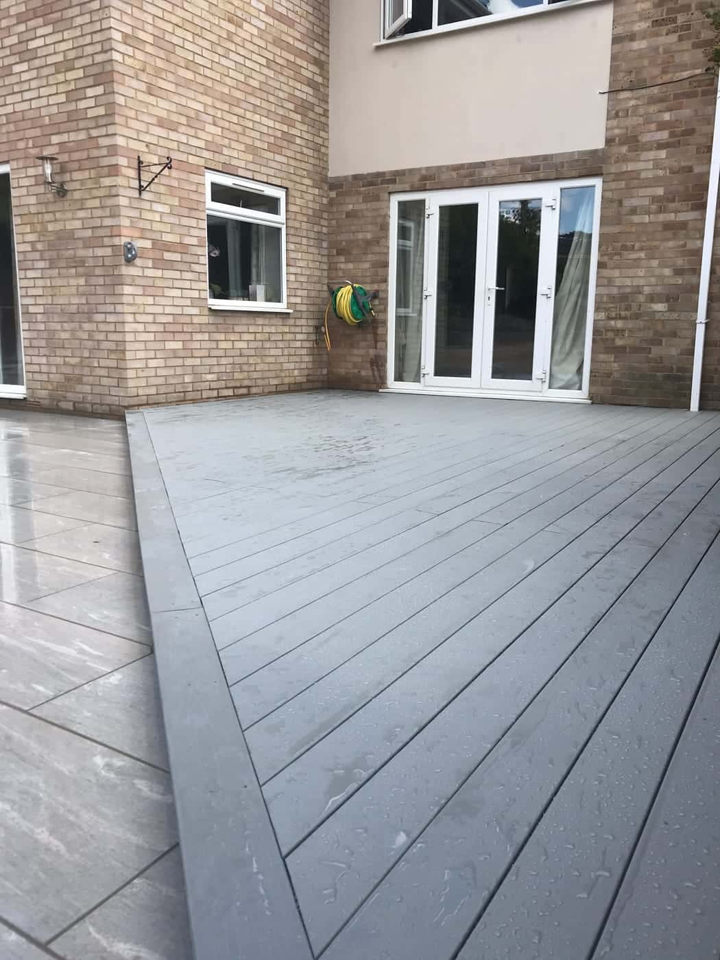 Grey composite decking beside new paving behind a house