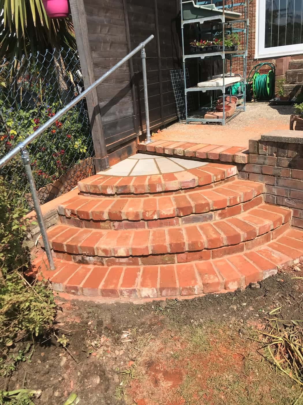 Curved red-brick garden steps with a handrail