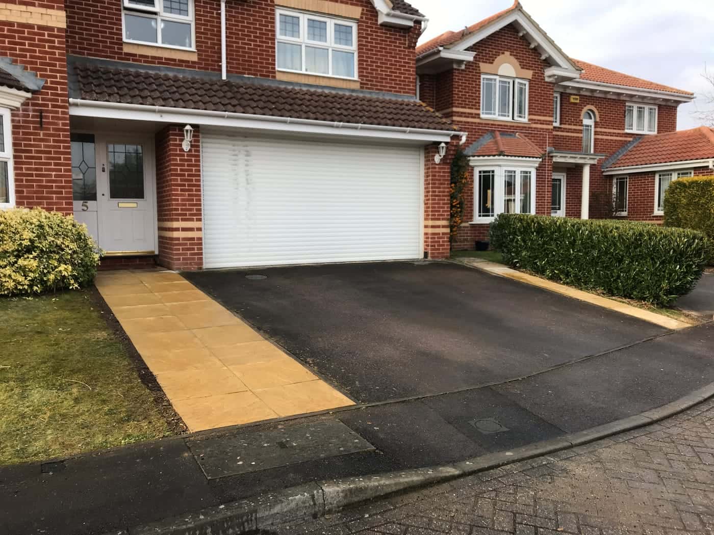 Driveway with a new paved path to the front door of a brick house