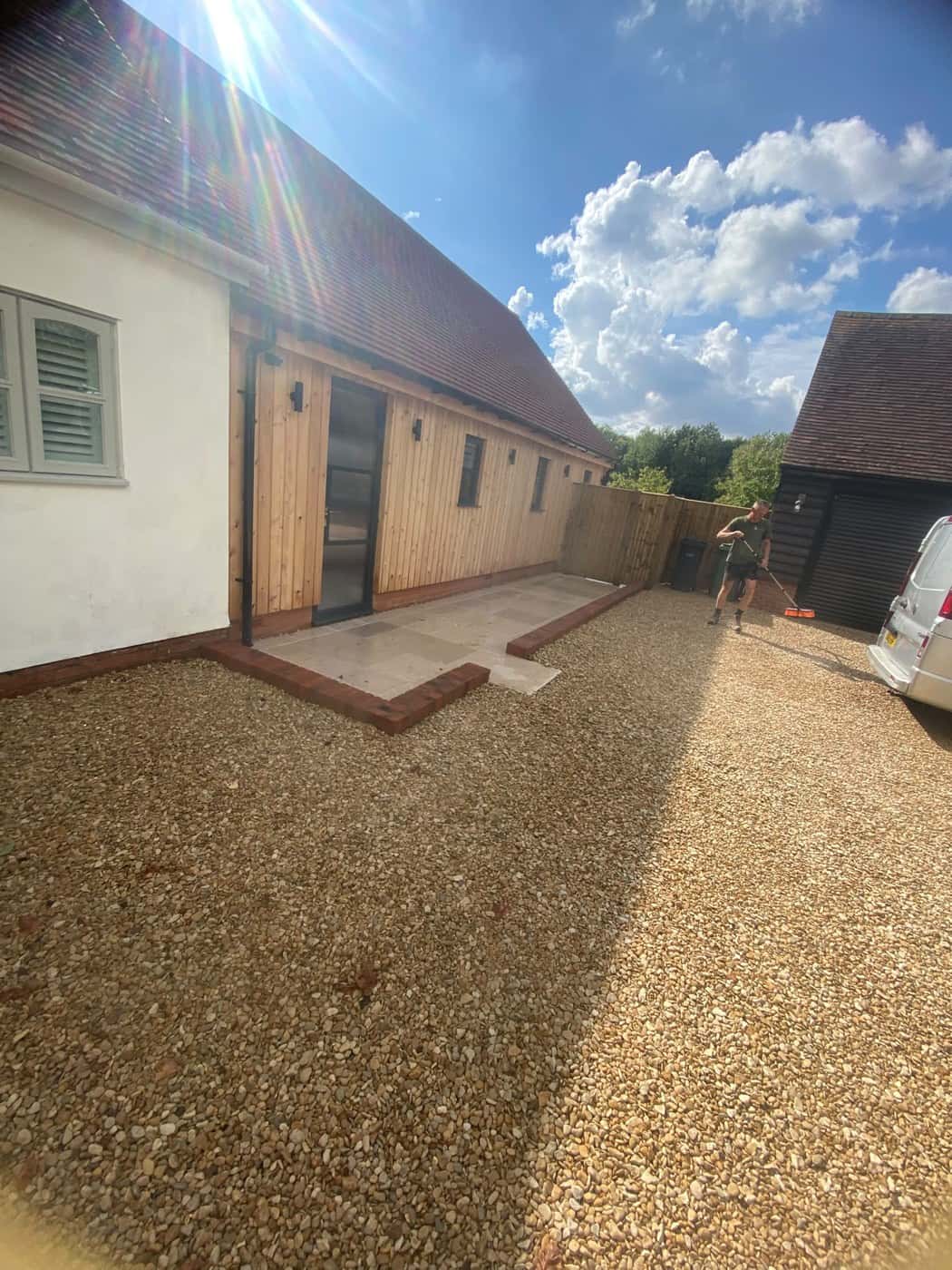Gravel drive and a brick-edged stone patio beside a timber-clad building