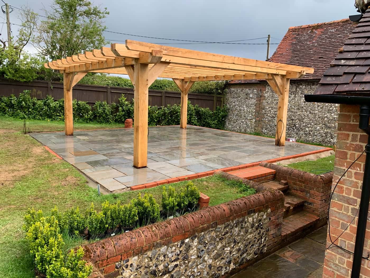 Garden with a timber pergola, stone patio and brick steps