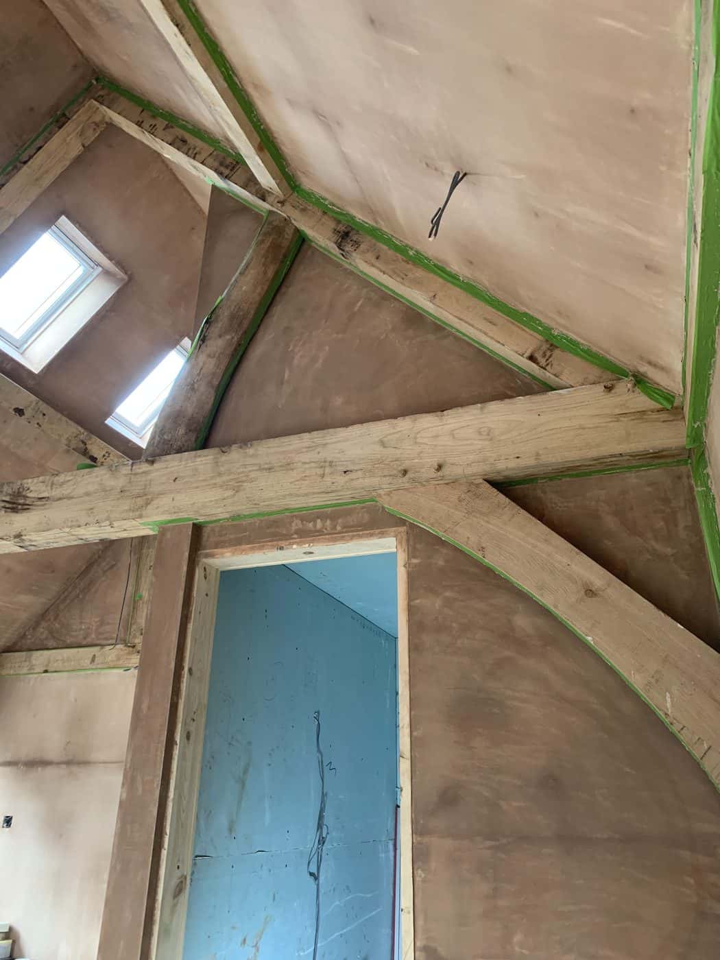 Freshly plastered vaulted ceiling and walls around exposed timber beams