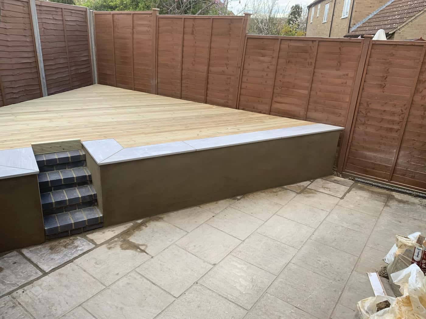 Raised timber decking and paving in a fenced garden