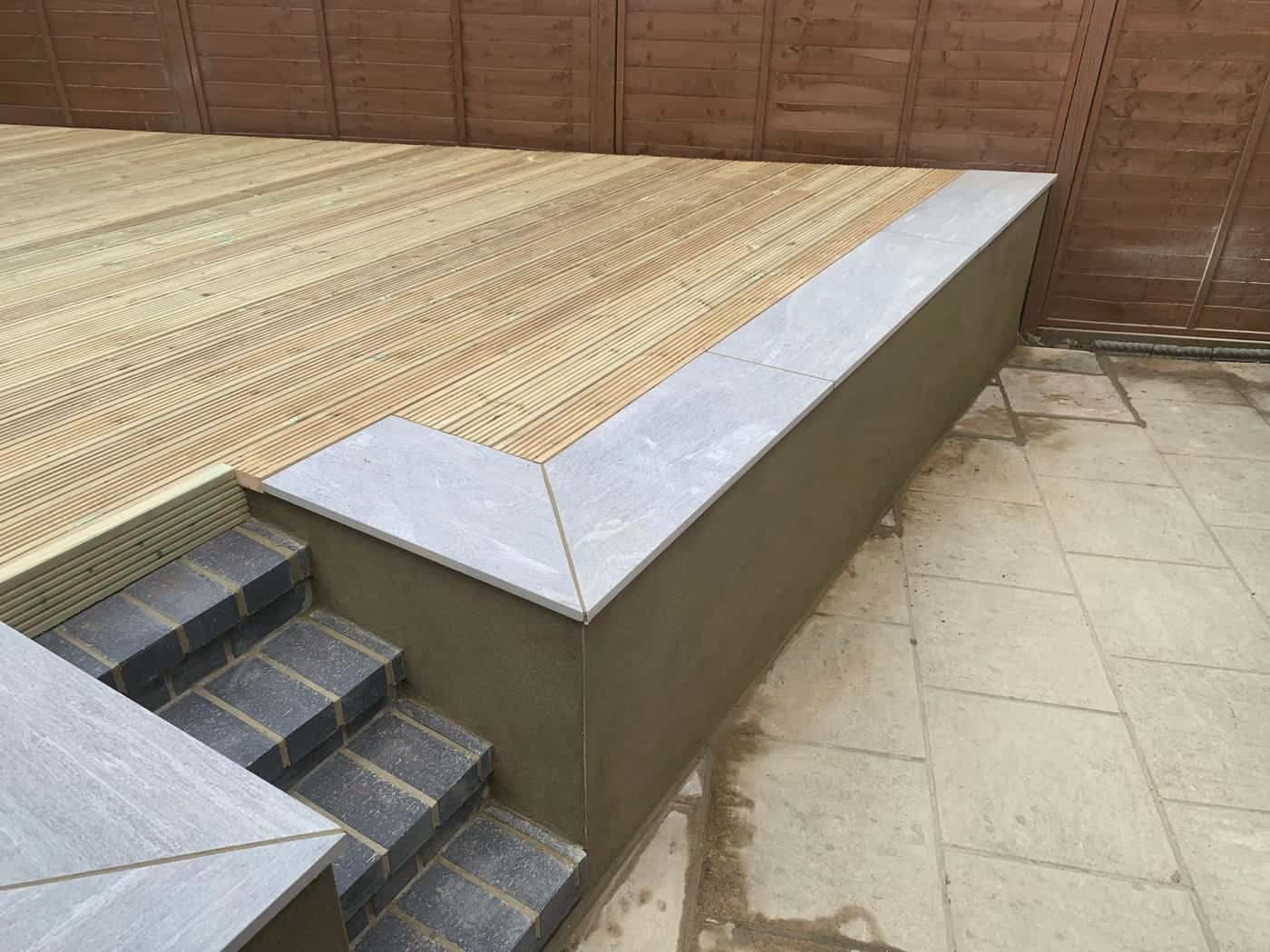 Raised timber decking with a rendered wall and tiled steps