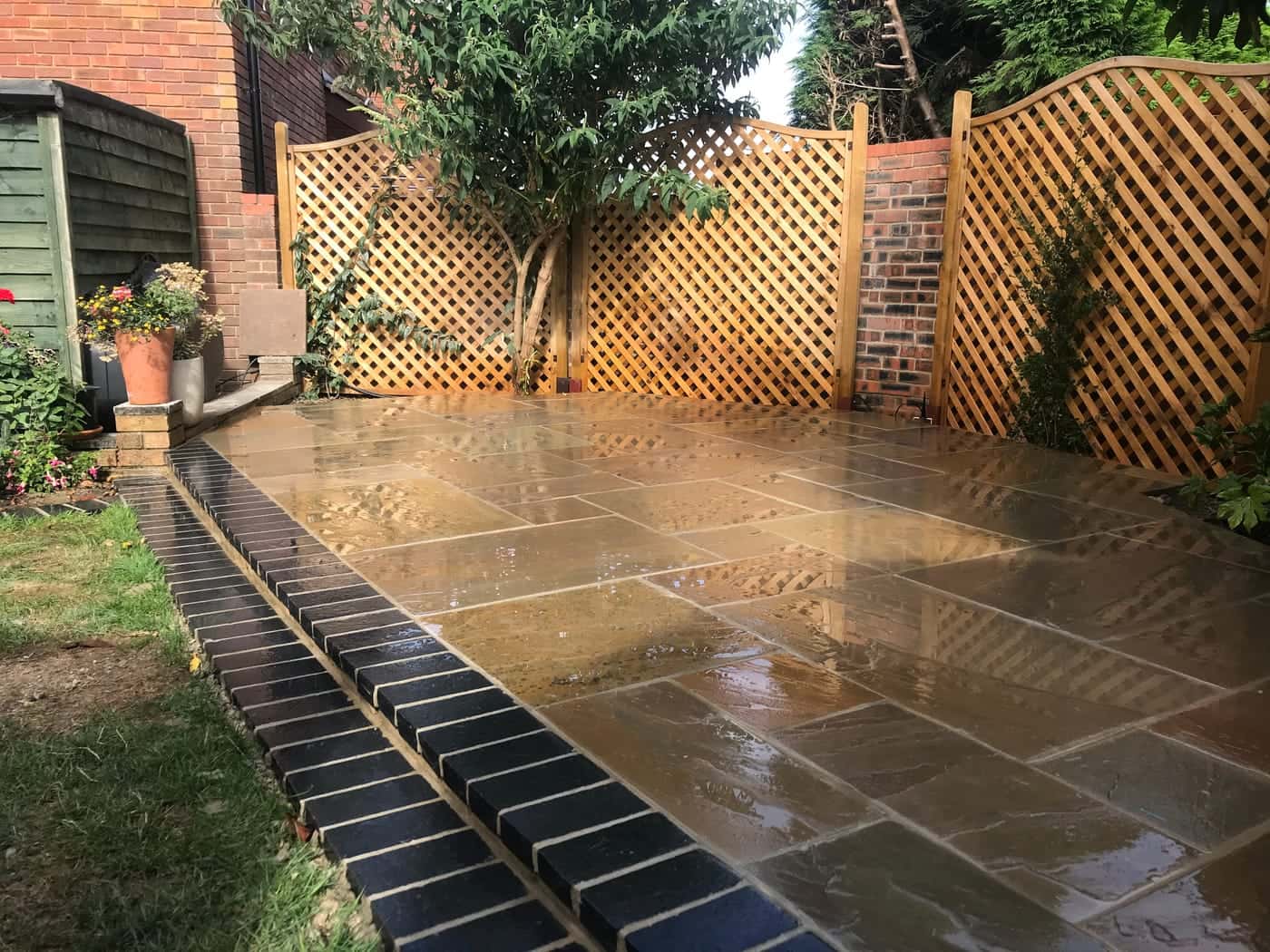 Sandstone patio with brick edging and trellis fencing